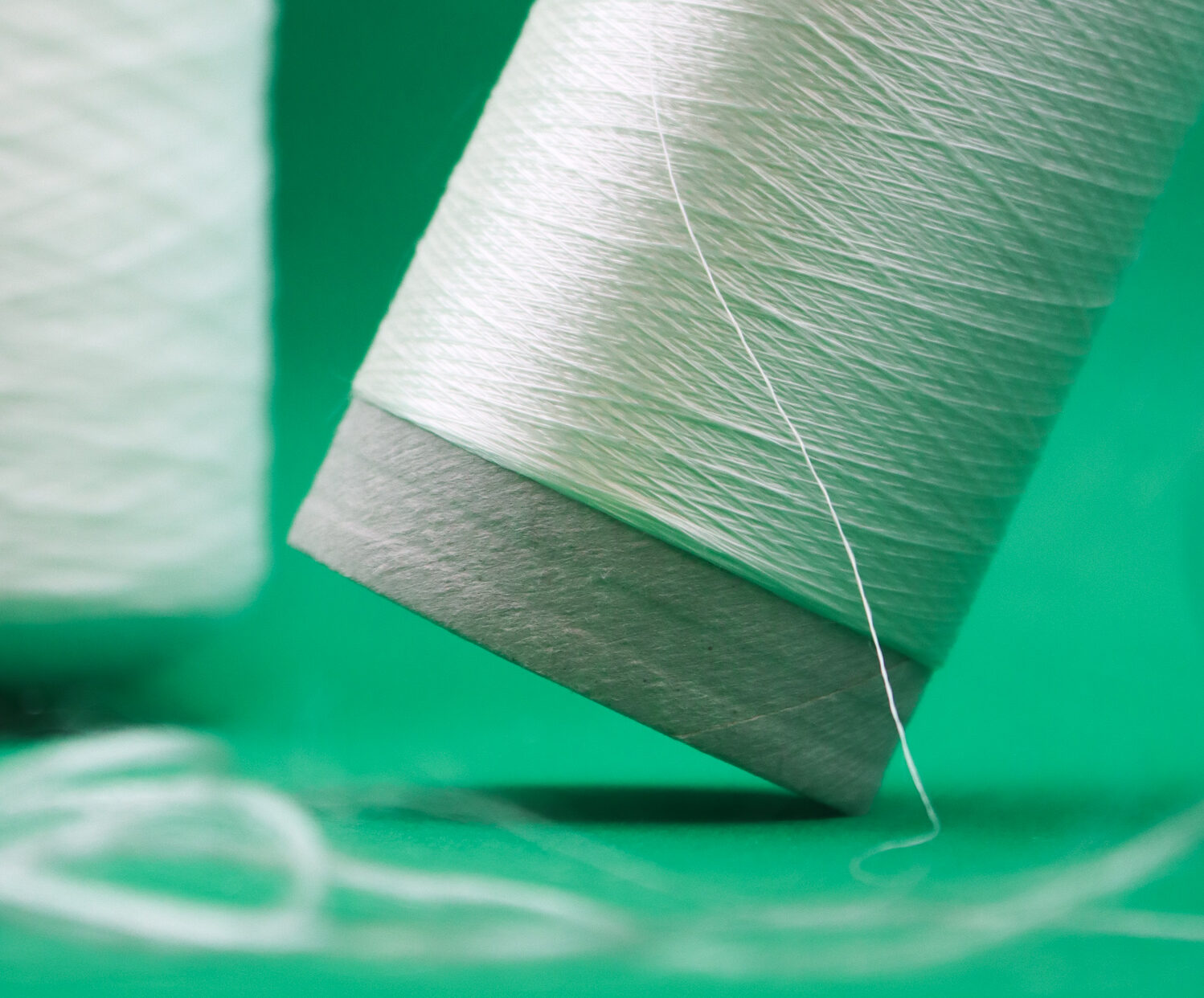 A spool of white AlgiKnit yarn on a green background. Keel Labs was formerly known as AlgiKnit.